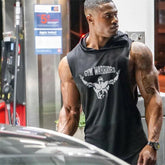 Man wearing a black sleeveless hoodie with 'Gym Warriors' logo at a gas station.