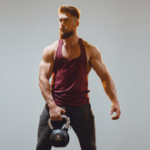 Man holding a kettlebell in front of illuminated letters on a wall.