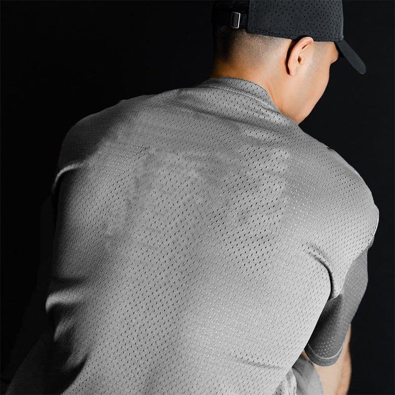 Person wearing a gray athletic shirt with mesh design on a black background