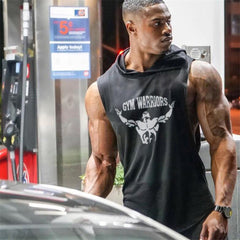 Man wearing a black sleeveless hoodie with 'Gym Warriors' logo at a gas station.