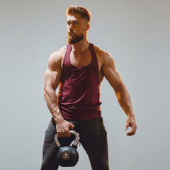 Man  holding a kettlebell in front of illuminated letters on a wall.